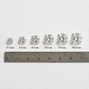 Loose cushion cut diamonds from 3.5mm to 10.0mm placed next to a metal metric ruler for scale.