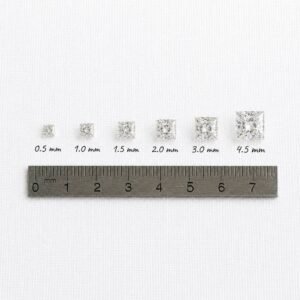 Loose princess cut diamonds from 0.5mm to 4.5mm placed next to a metal metric ruler for scale.