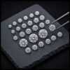 Collection of certified round brilliant loose lab grown diamonds displayed on a black slate with precision tweezers for wholesale diamond selection.